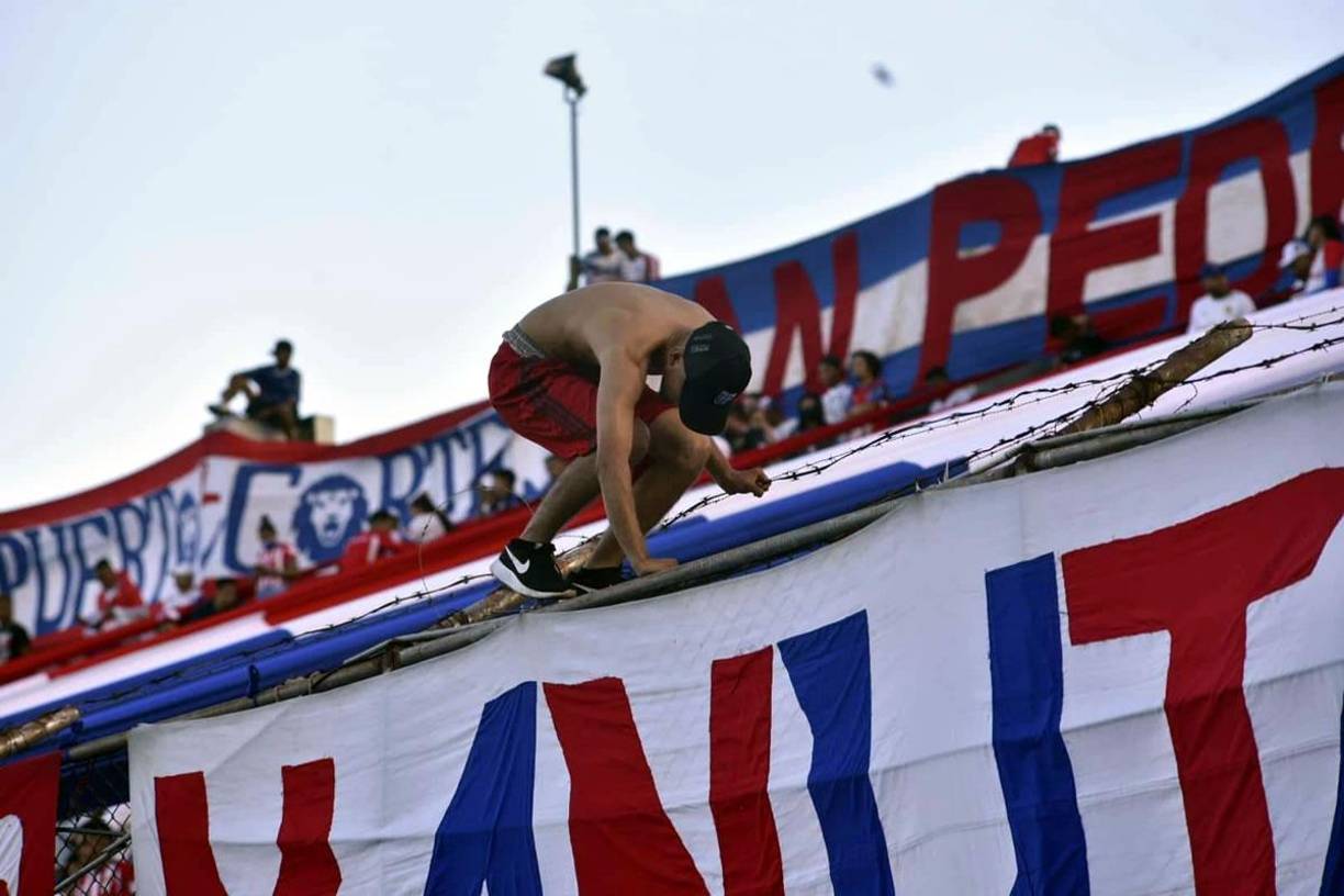 Este aficionado del Olimpia se ariesgó al subirse al alambrado del estadio Morazán para colocar una manta.