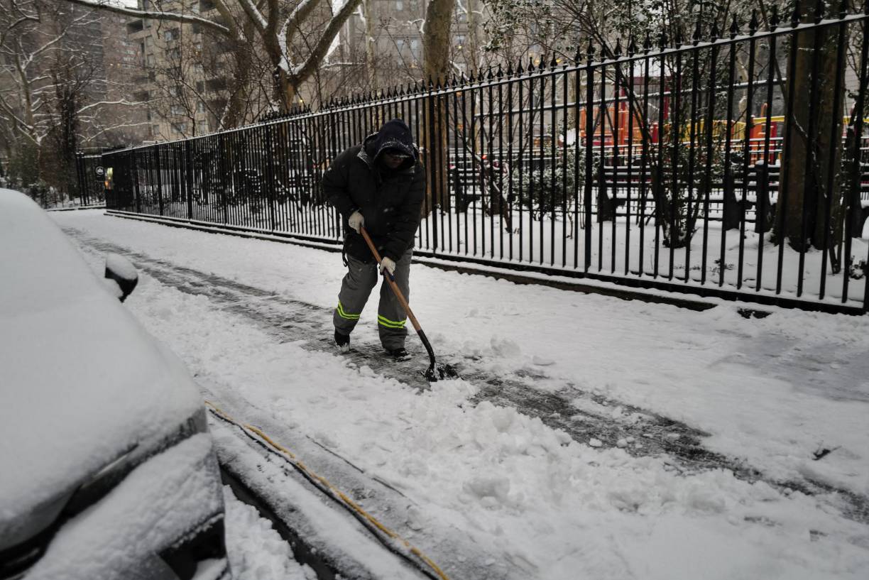 A municipal worker removes snow from the sidewalk in the Manhattan borough of New York city on January 16, 2024. (Photo by Charly TRIBALLEAU / AFP)
