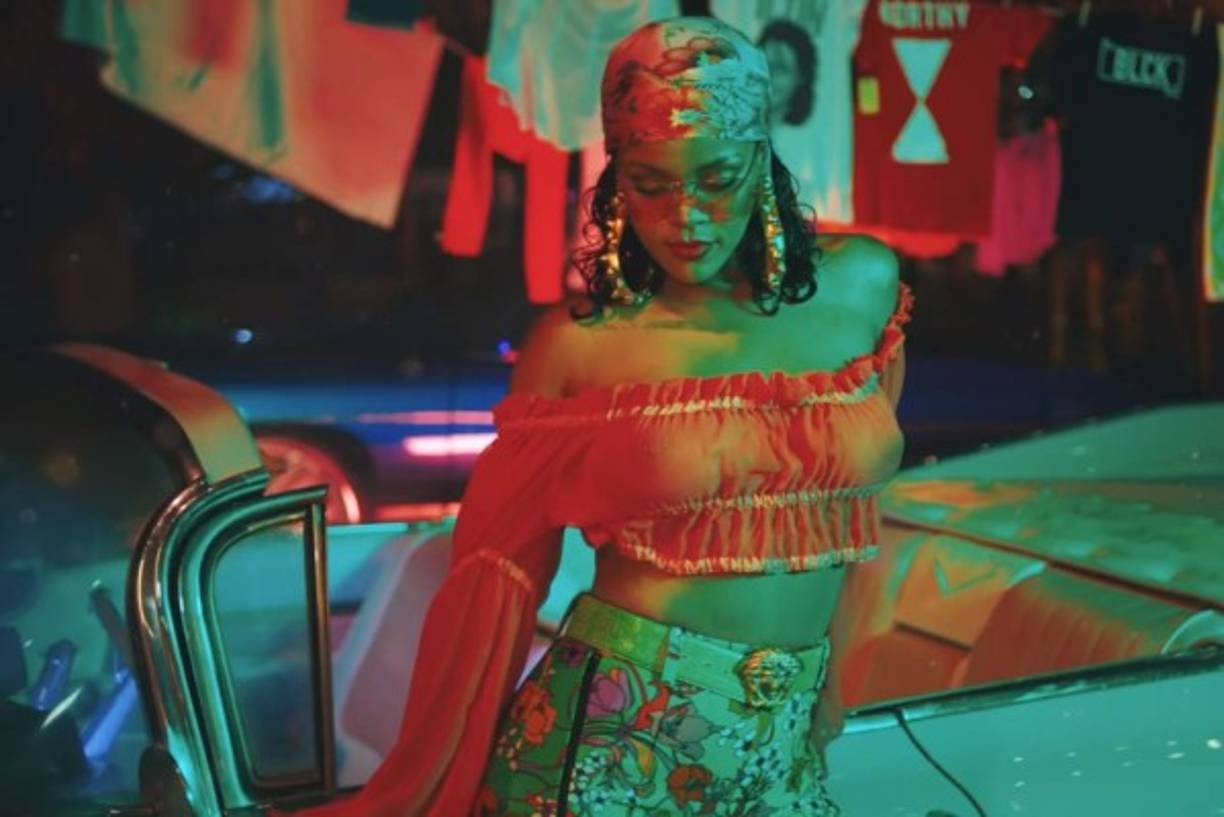 Rihanna aparece más provocativa que nunca. Con su pañuelo en la cabeza, el pantalón verde fluorescente y ese top rosa transparente que ha revolucionado, sobre todo porque deja ver sus pezones.