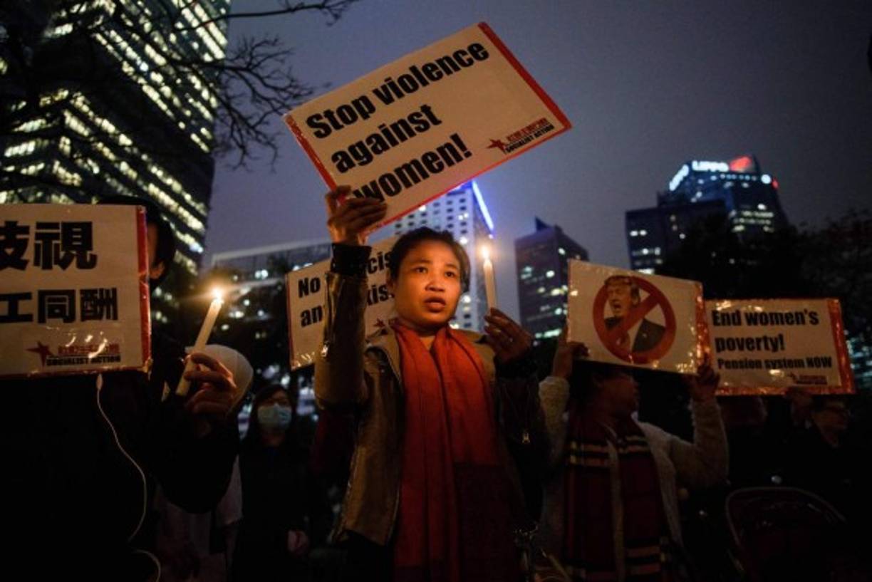 Participantes del Día Internacional de la mujer en Hong Kong llevan candelas y pancartas contra Donald Trump.