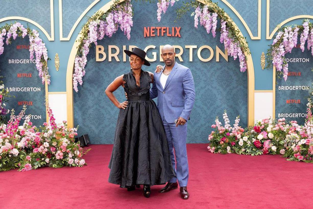  Adjoa Andoh también optó por un vestido negro largo que tenía mangas con volantes y un escote pronunciado. En su verdadero estilo Lady Danbury, Andoh agregó un sombrero negro para completar su look. Daniel Francis, su hermano en la serie lució elegante en su traje azul.