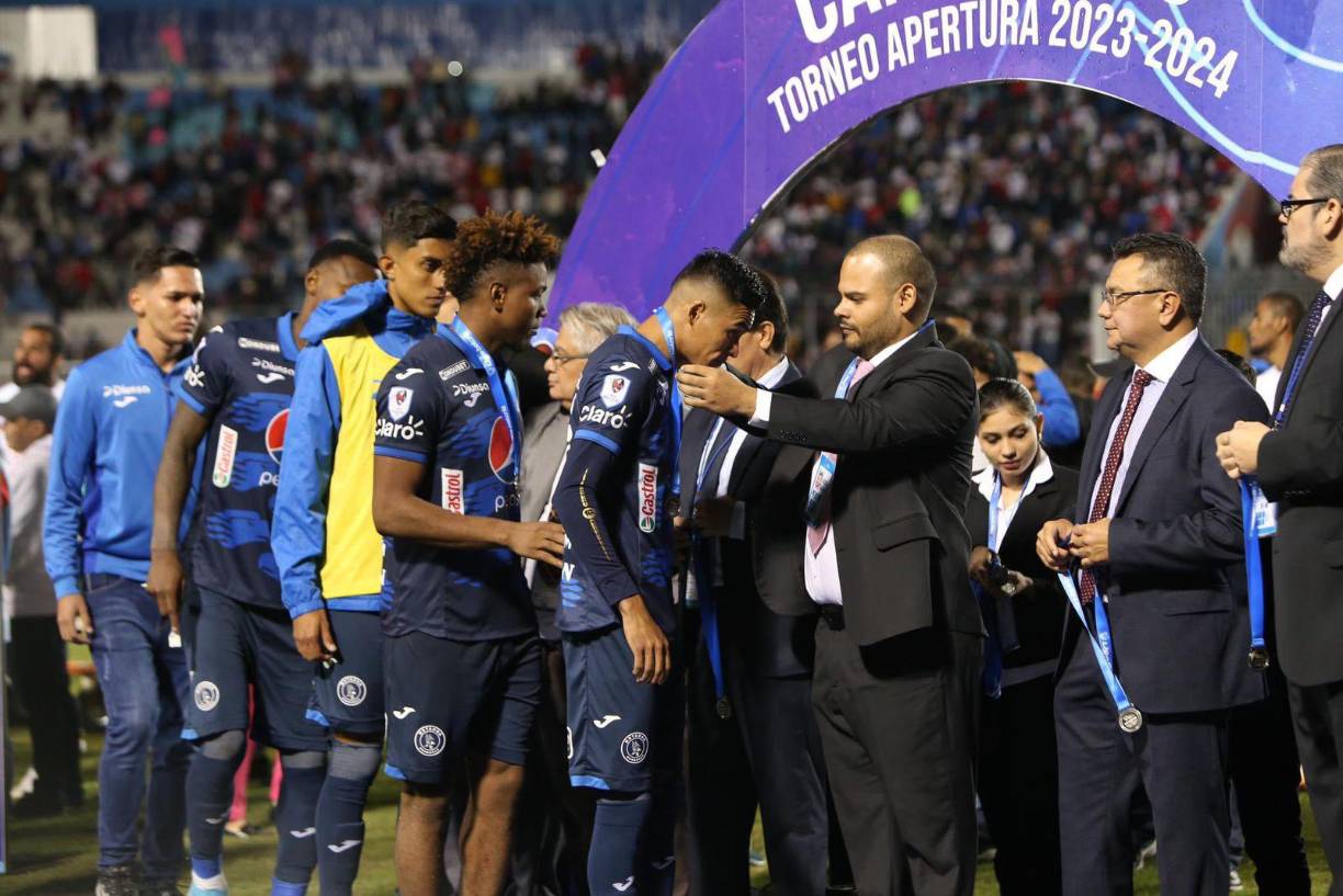 Yeison Mejía y Juan Delgado reciben las medallas de subcampeón del Motagua. Al final, el ciclón no pudo conquistar el título de Liga Nacional.