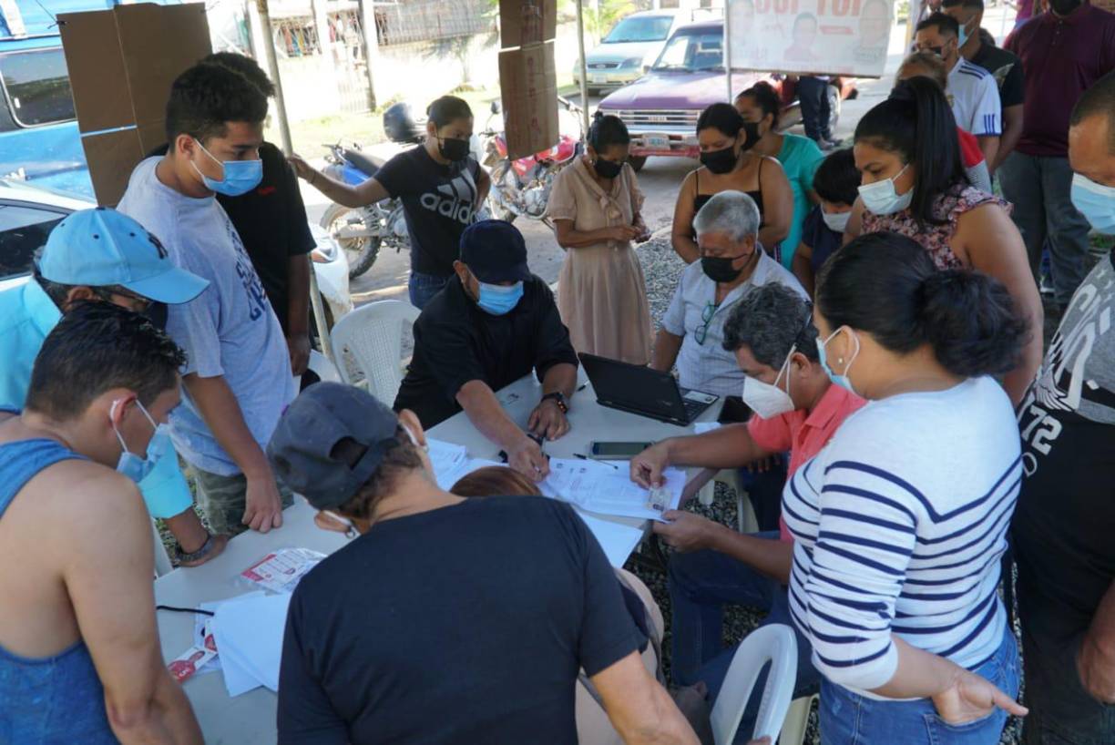 Los representantes de mesa mientras cotejan las identidades de los votantes.