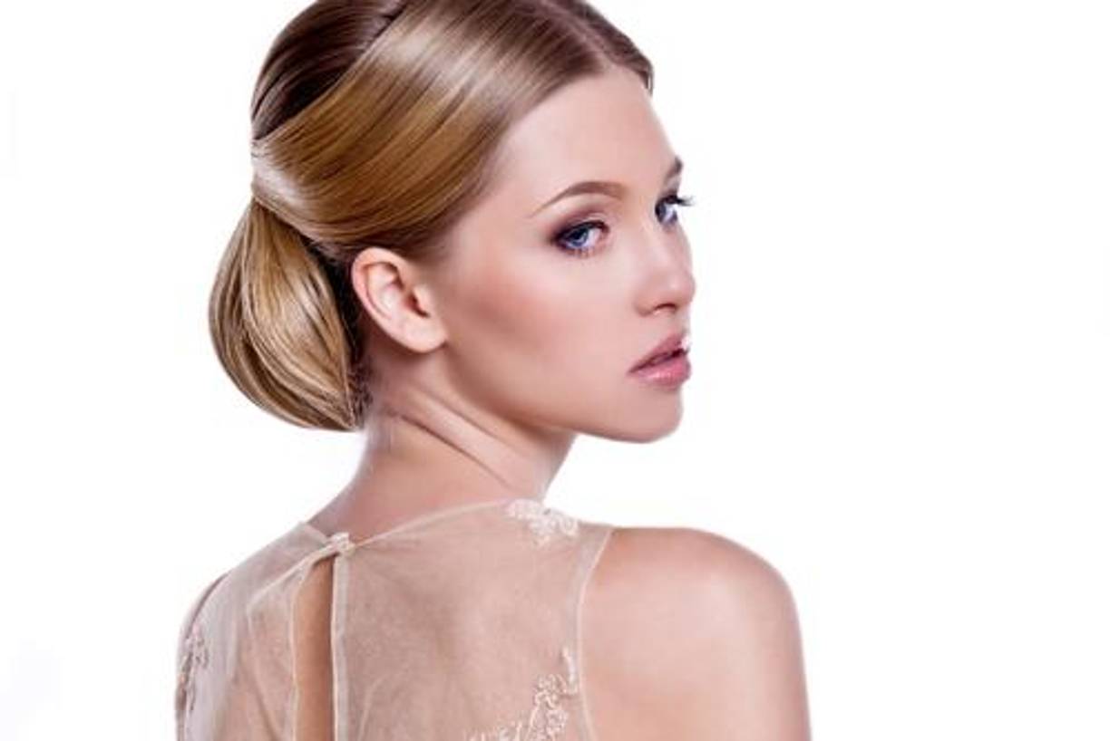 Moños pulidos bajos: El moño bajo, un clásico de la elegancia, retorna esta temporada en su versión pulida, aportando sofisticación y un aire minimalista. Este estilo es ideal para las novias que buscan un peinado más formal y refinado que siempre favorece y que permite jugar con el lugar hacia el que colocar la raya del cabello.