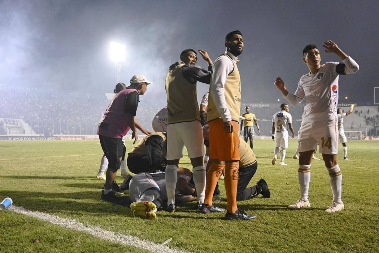 Los jugadores del Comunicaciones se protegen con las manos tras la bengala que agredió a su compañero Stheven Robles.