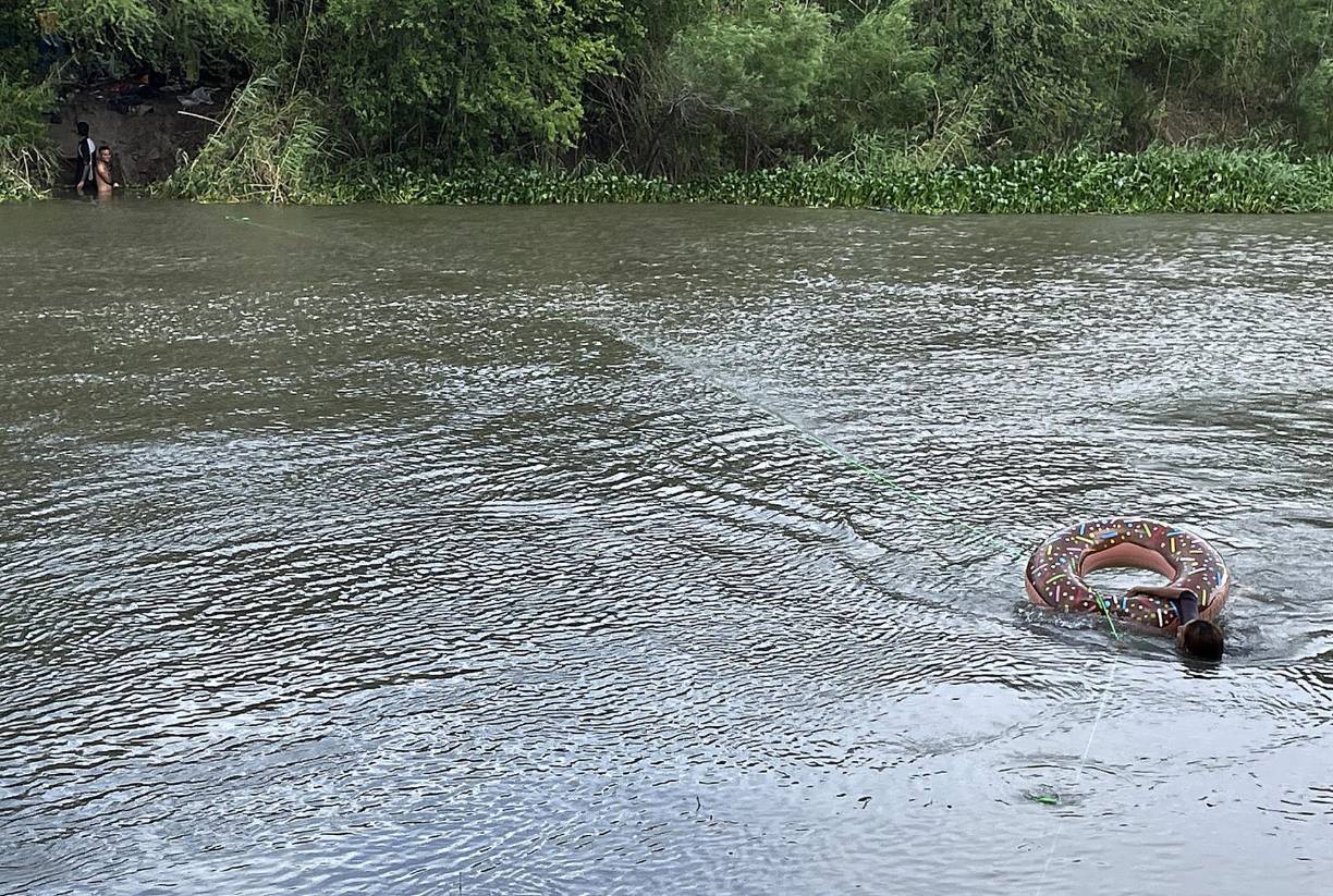 Los migrantes cruzan en flotadores que son atados a una soga del otro lado del río y así desafían las fuertes corrientes.