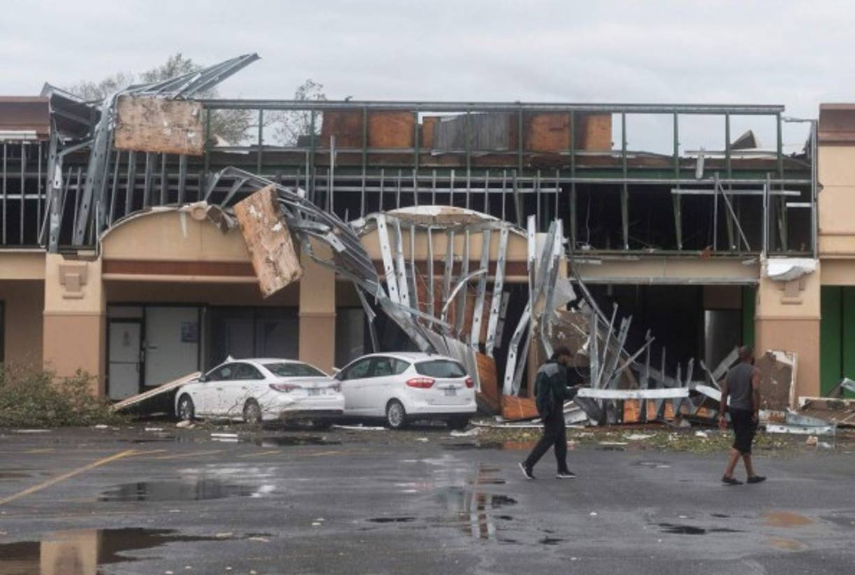 People walk past a destroyed building after the passing of Hurricane Laura in Lake Charles, Louisiana on August 27, 2020. - Hurricane Laura slammed into the southern US state of Louisiana Thursday and the monster category 4 storm prompted warnings of 'unsurvivable' ocean surges and evacuation orders for hundreds of thousands of Gulf Coast residents. The National Hurricane Center (NHC) said 'extremely dangerous' Laura would bring winds of 150 miles per hour (240 kilometers per hour) and 'destructive waves will cause catastrophic damage' to Louisiana and Texas. (Photo by ANDREW CABALLERO-REYNOLDS / AFP)