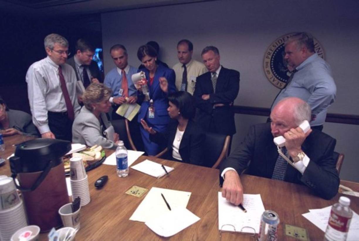 Cheney habla por teléfono mientras Rice da indicaciones a miembros del gabinete presidencial.