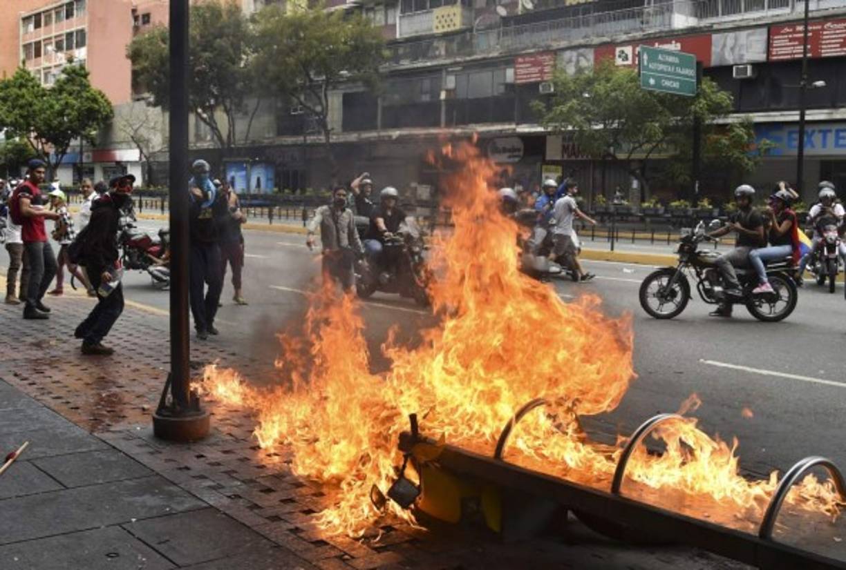 A protester burns a motorcycle during clashes with the security forces in a protest against the government of President Nicolas Maduro on the anniversary of the 1958 uprising that overthrew the military dictatorship, in Caracas on January 23, 2019. - Venezuela's National Assembly head Juan Guaido declared himself the country's 'acting president' on Wednesday during a mass opposition rally against leader Nicolas Maduro. (Photo by YURI CORTEZ / AFP)