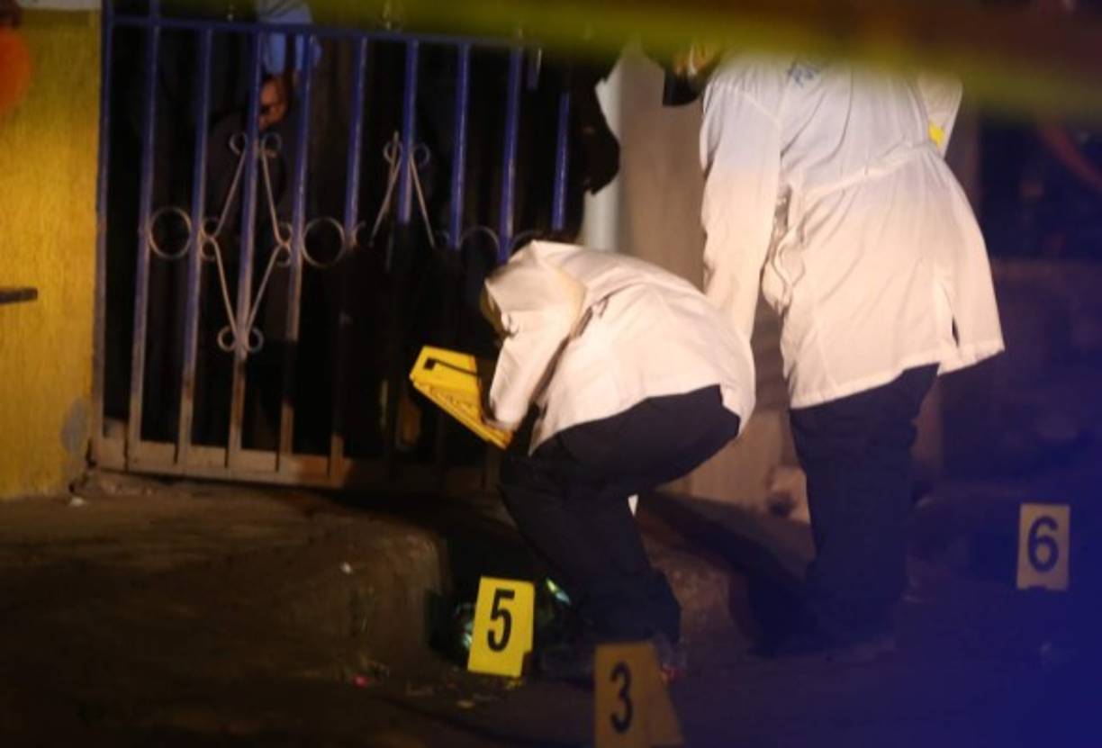 Agentes del Ministerio Público (Fiscalía) y de la Policía Nacional de Honduras realizan las investigaciones en el lugar del crimen múltiple.