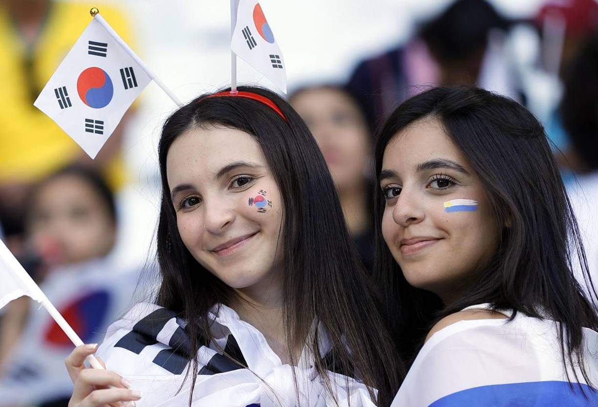 Una aficionada surcoreana y una uruguaya posando para la cámara en el Education City Stadium.
