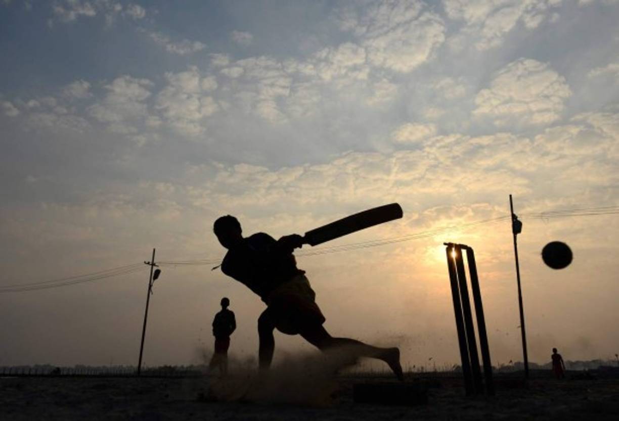 Estudiantes juegan al críquet bajo un majestuoso amanecer en la India.