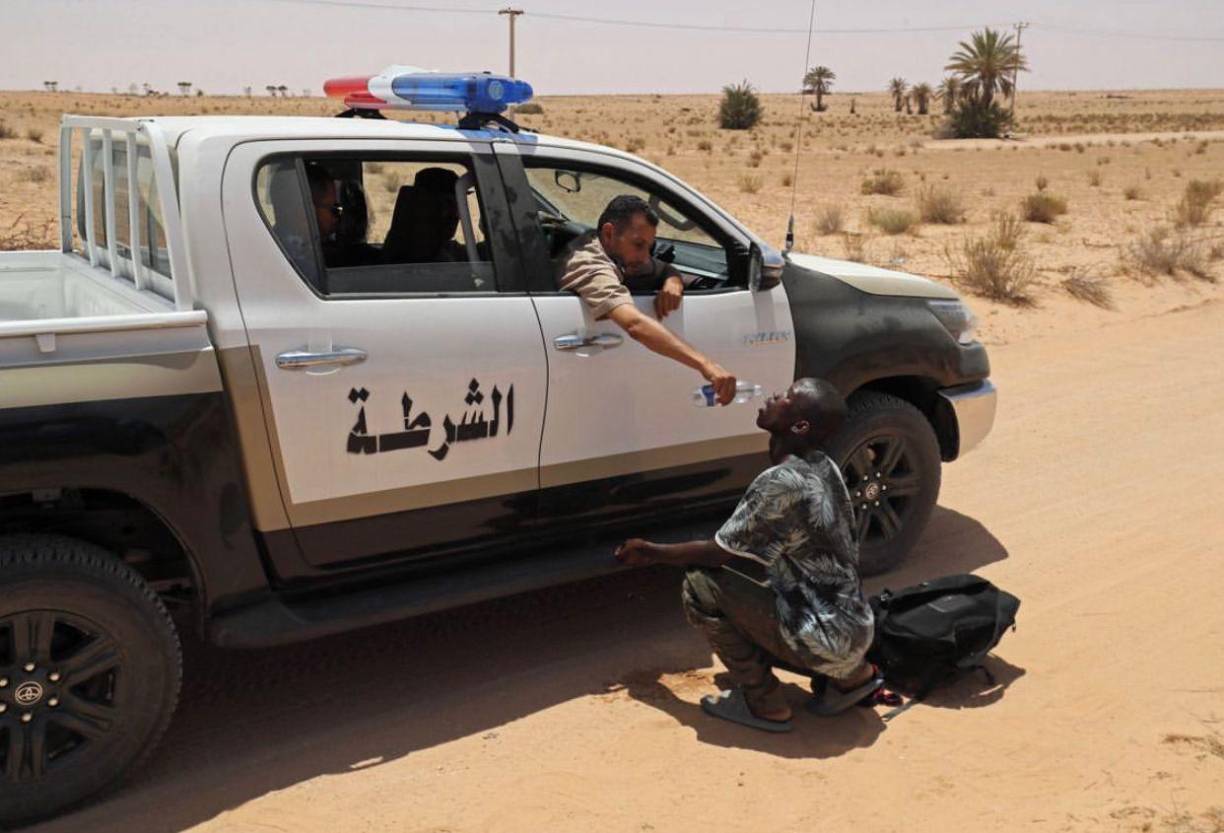 <b>05.</b> Un guardia fronterizo libio da agua a un migrante durante una operación de rescate en una zona deshabitada cerca de la ciudad fronteriza de Al-Assah el 16 de julio de 2023.⁣⁣
