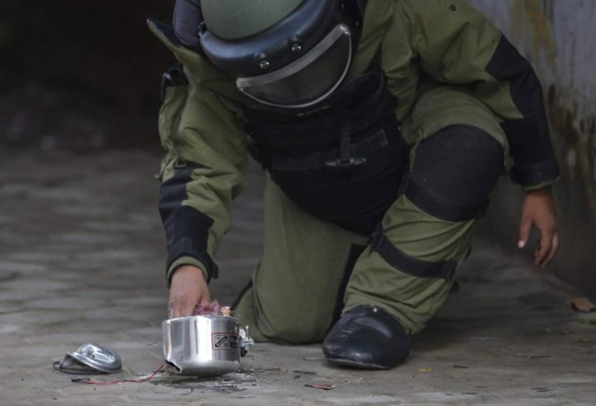 NEPAL. Concentración para desarmar bomba. Un artificiero manipula una olla a presión, usada como bomba casera, mientras intenta desarmarla cerca de un colegio en Katmandú. Foto: EFE/Narendra Shrestha