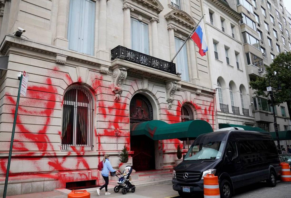 Una mujer empuja a un niño en un cochecito frente al consulado ruso en Nueva York después de que fue destrozado con pintura en aerosol roja el viernes temprano en una aparente protesta mientras el presidente Vladimir Putin persigue su sangrienta invasión de Ucrania. 