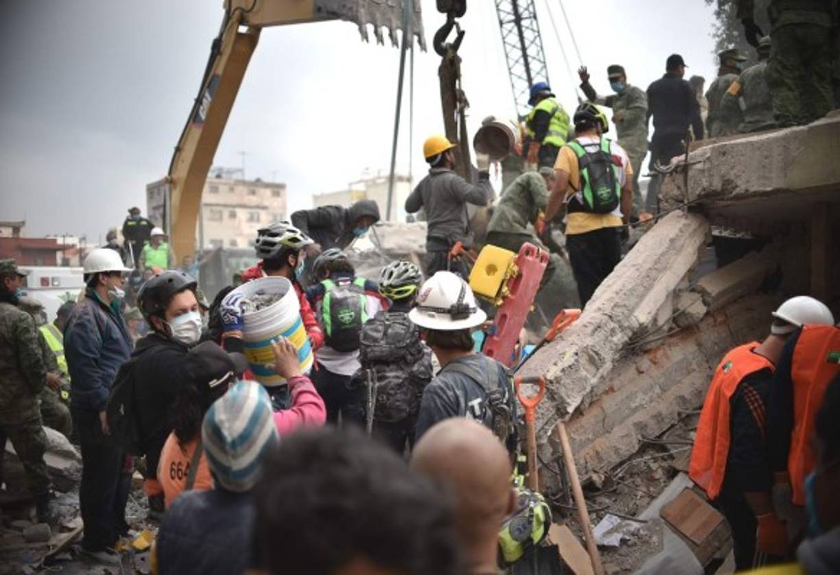 Volunteers remove rubble during the search for survivors in a flattened building in Mexico City on September 20, 2017 after a strong quake hit central Mexico on the eve killing at least 240 people.<br/>A powerful 7.1 earthquake shook Mexico City on Tuesday, causing panic among the megalopolis' 20 million inhabitants on the 32nd anniversary of a devastating 1985 quake. / AFP PHOTO / Yuri CORTEZ
