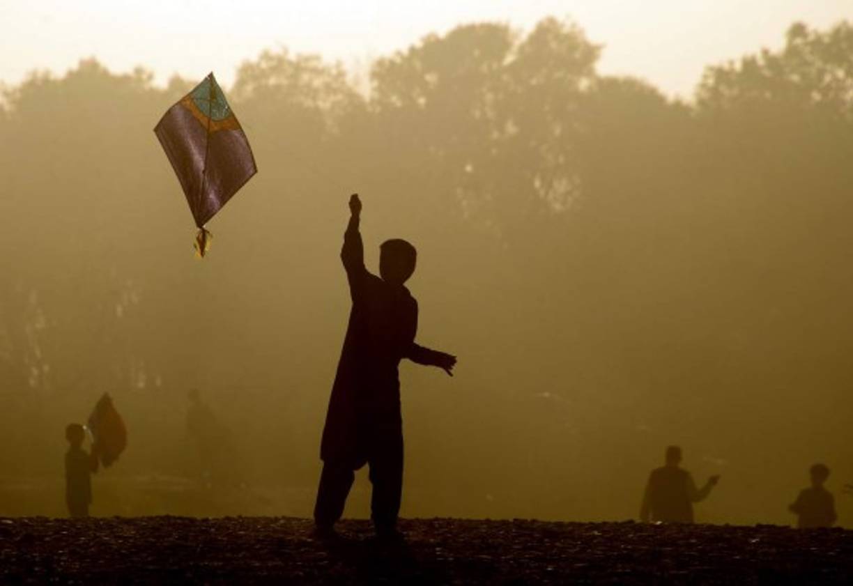 AFGANISTÁN. Niños ante todo. Niños afganos juegan con su cometa al atardecer, en las afueras de Herat. Foto: AFP/Aref Karimi