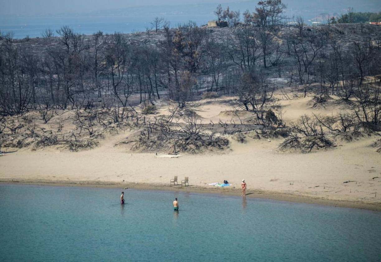 <b>08. </b>Una mujer entra al mar desde una playa donde los incendios forestales destruyeron el bosque, en Glystra, cerca del pueblo de Gennadi, en la parte sur de la isla griega de Rodas, el 27 de julio de 2023. ⁣⁣