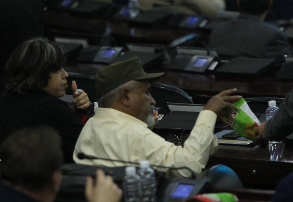 El diputado Juan Barahona toma de un snack que le comparte un compañero de Libre.