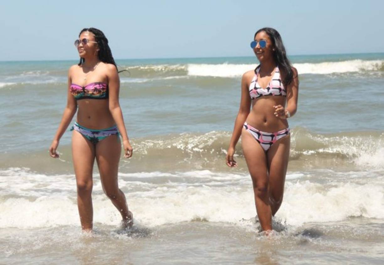 Dos chicas hondureñas caminan por la orilla del mar mientras disfrutan del sol.