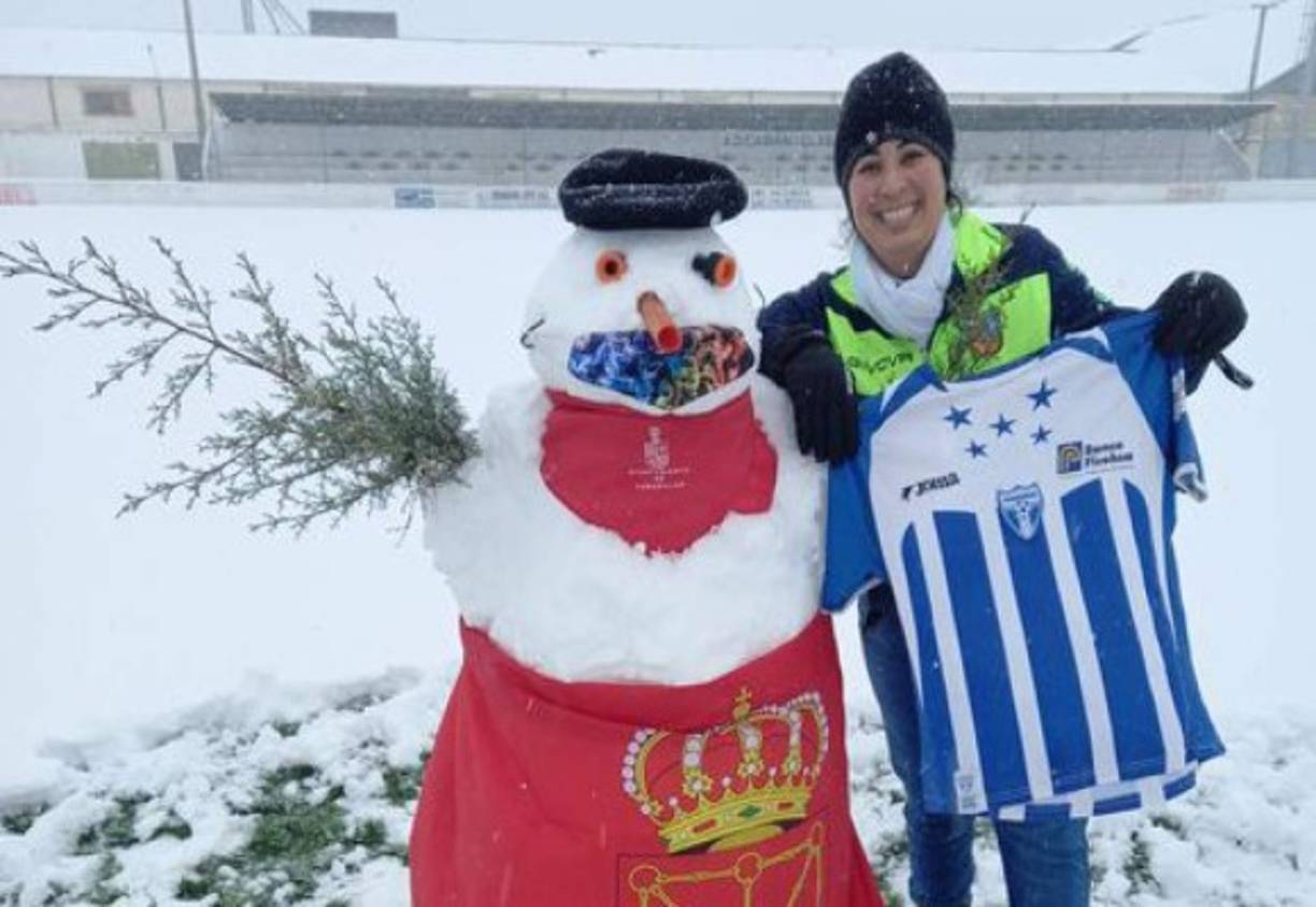 Una joven hondureña muestra una caminsa de la Selección de fútbol a la par de un muñeco de nieve en España.