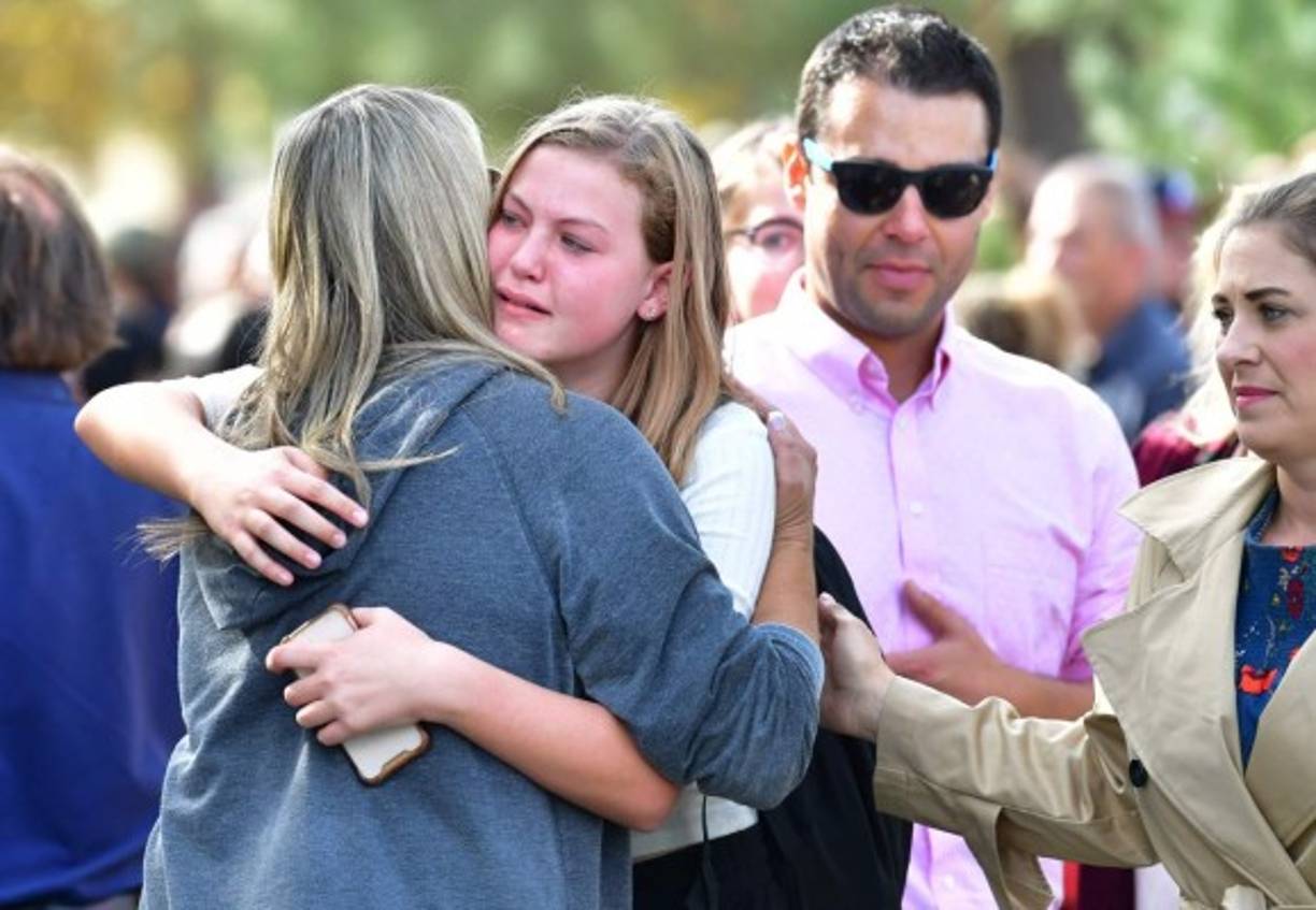 Students and parents embrace after being picked up at Central Park, after a shooting at Saugus High School in Santa Clarita, California on November 14, 2019. - At least four people were injured in a shooting at a high school north of Los Angeles Thursday, triggering a police hunt for the suspect who was later taken into custody.One female was killed Thursday, hospital officials said. The suspect was in custody and taken to a hospital for treatment, while at least three others were injured in the shooting at Saugus High School in Santa Clarita, 40 miles (65 kilometers) north of Los Angeles.'One female deceased patient. Two critical male patients. One male patient in good condition,' tweeted the nearby Henry Mayo Hospital in Valencia.No further details of the deceased were provided. (Photo by Frederic J. BROWN / AFP)
