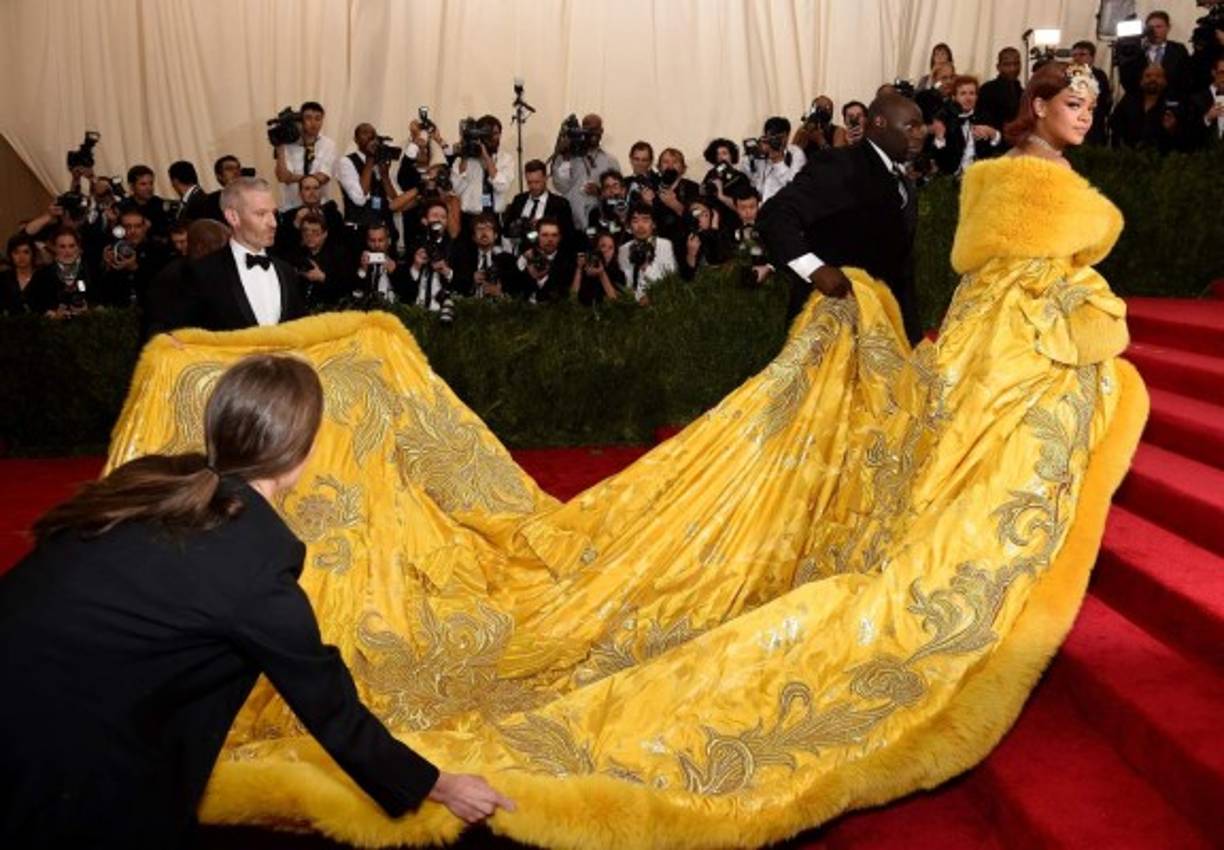 La cantante Rihanna tuvo que recibir ayuda para poder caminar por la alfombra roja debido a lo largo de su capa.