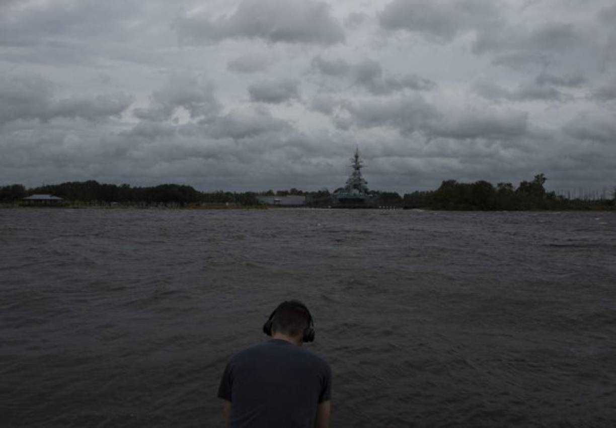 Un hombre escucha música junto al río Cape Fear cuando llega el huracán Florence en Wilmington, Carolina del Norte.