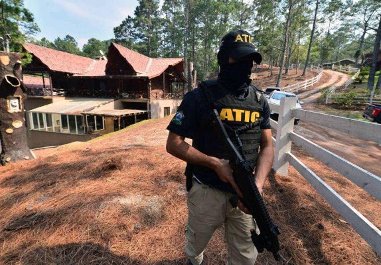 Un agente de la Atic resguarda la casa de campo de la ex primera dama Rosa Bonilla de Lobo. AFP
