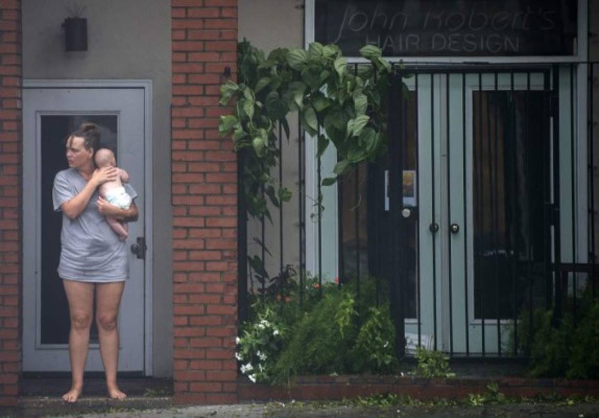 Una mujer y su bebé esperan una de las lanchas para salir de su residencia ante el aumento de las aguas por las fuertes lluvias.