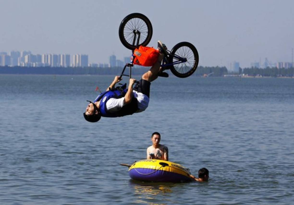 CICLISMO. Deporte extremo. Un entusiasta del ciclismo extremo realiza una acrobacia con una bicicleta antes de caer en el lago del Este en Wuhan, provincia de Hubei, China.