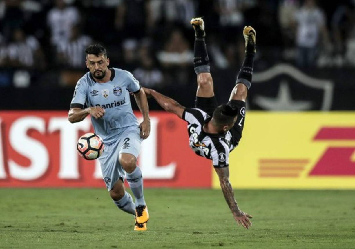 FÚTBOL. Caída estrepitosa. Edilson, jugador del Gremio, controla el balón mientras Leo Valencia, del Botafogo, cae aparatosamente en el duelo por la Copa Libertadores.
