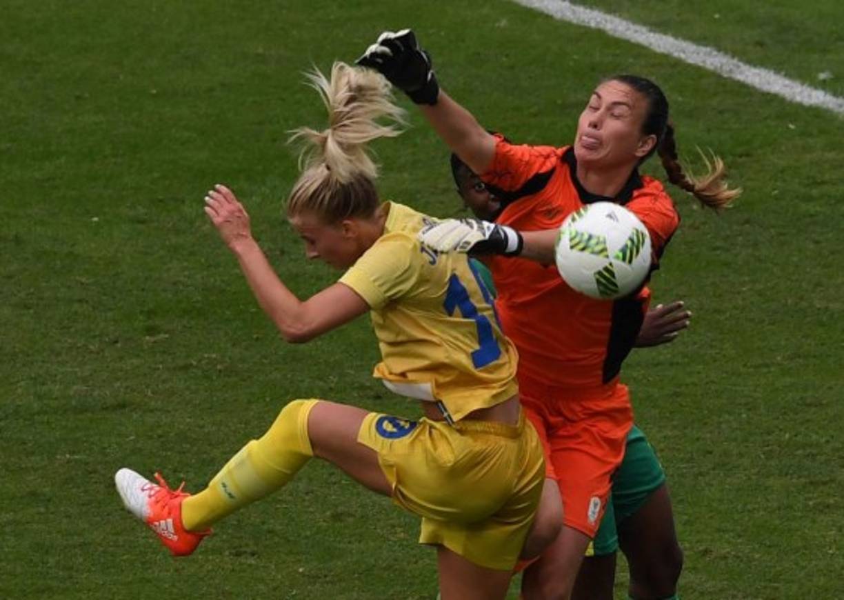 FÚTBOL FEMENINO. Disputa. La jugadora Sueca Sofía Jakobsson (izquierda) compite por el balón con la portera de Sudáfrica, Roxanne Barker, en un partido entre ambas selecciones en Río de Janeiro. Fotos: AFP