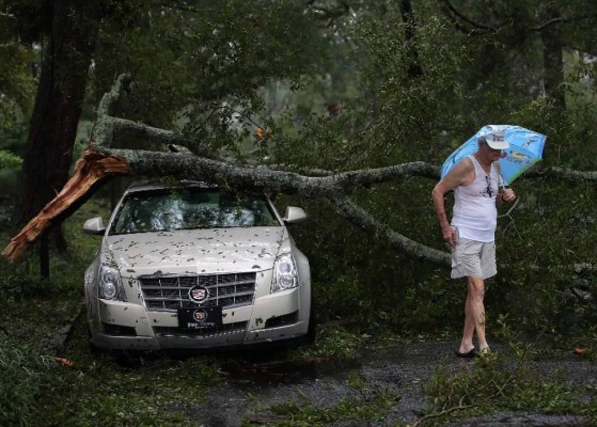 WILMINGTON, NC - SEPTEMBER 16: Robert Dolman walks past a Cadillac that has a large tree limb on it, on September 16, 2018 in Wilmington, North Carolina. Hurricane Florence hit Wilmington as a category 1 storm causing widespread damage and flooding across North Carolina. Mark Wilson/Getty Images/AFP