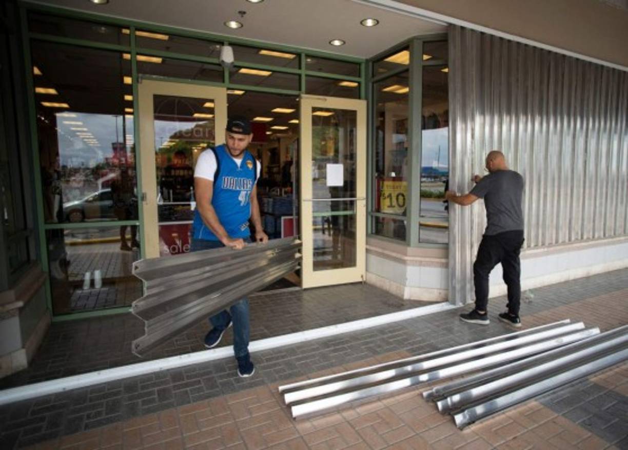 CORRECTION - Workers prepare the building outside a store for the arrival of Tropical Storm Dorian in Humacao, Puerto Rico on, August 28, 2019. - Tropical Storm Dorian bore down on Puerto Rico Wednesday as residents braced for a direct hit, the first since the island was ravaged two years ago by Hurricane Maria. US forecasters said they expected Dorian to make landfall in populous eastern Puerto Rico at near hurricane strength later in the day. A hurricane watch also was up for the US Virgin Islands. (Photo by Eric Rojas / AFP) / The erroneous mention[s] appearing in the metadata of this photo by Eric Rojas has been modified in AFP systems in the following manner: [August 28, 2019] instead of [August 2, 2019]. Please immediately remove the erroneous mention[s] from all your online services and delete it (them) from your servers. If you have been authorized by AFP to distribute it (them) to third parties, please ensure that the same actions are carried out by them. Failure to promptly comply with these instructions will entail liability on your part for any continued or post notification usage. Therefore we thank you very much for all your attention and prompt action. We are sorry for the inconvenience this notification may cause and remain at your disposal for any further information you may require.