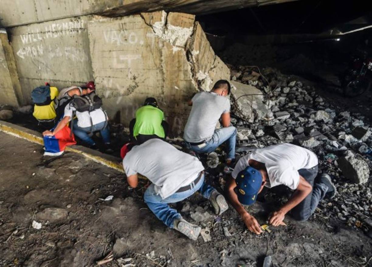 Los opositores se ocultan bajo un puente tras ser gaseados por la policía.