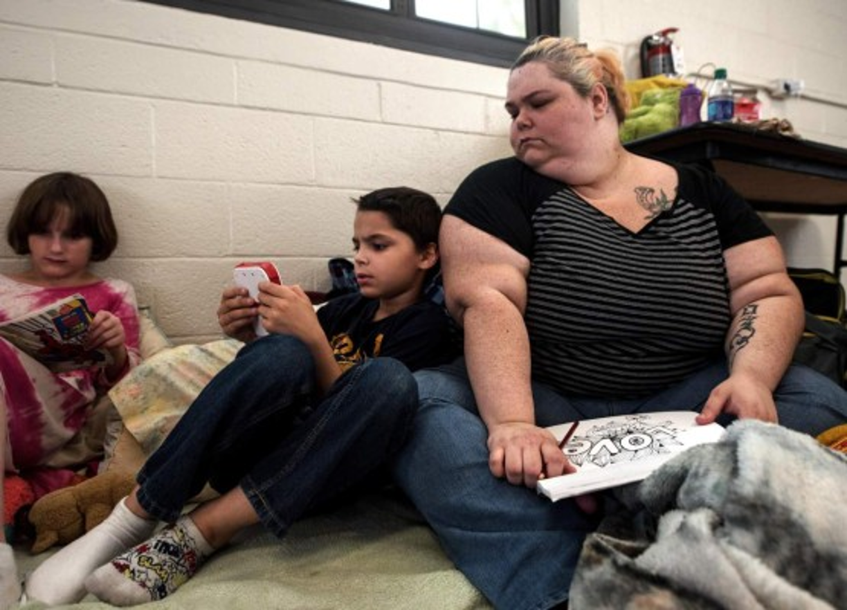 Kida Lee, de diez años, lee un libro a su hermano Jude mientras él juega y su madre, Jennifer Carty, los observa antes de la llegada prevista del Huracán Florence.<br/><br/>