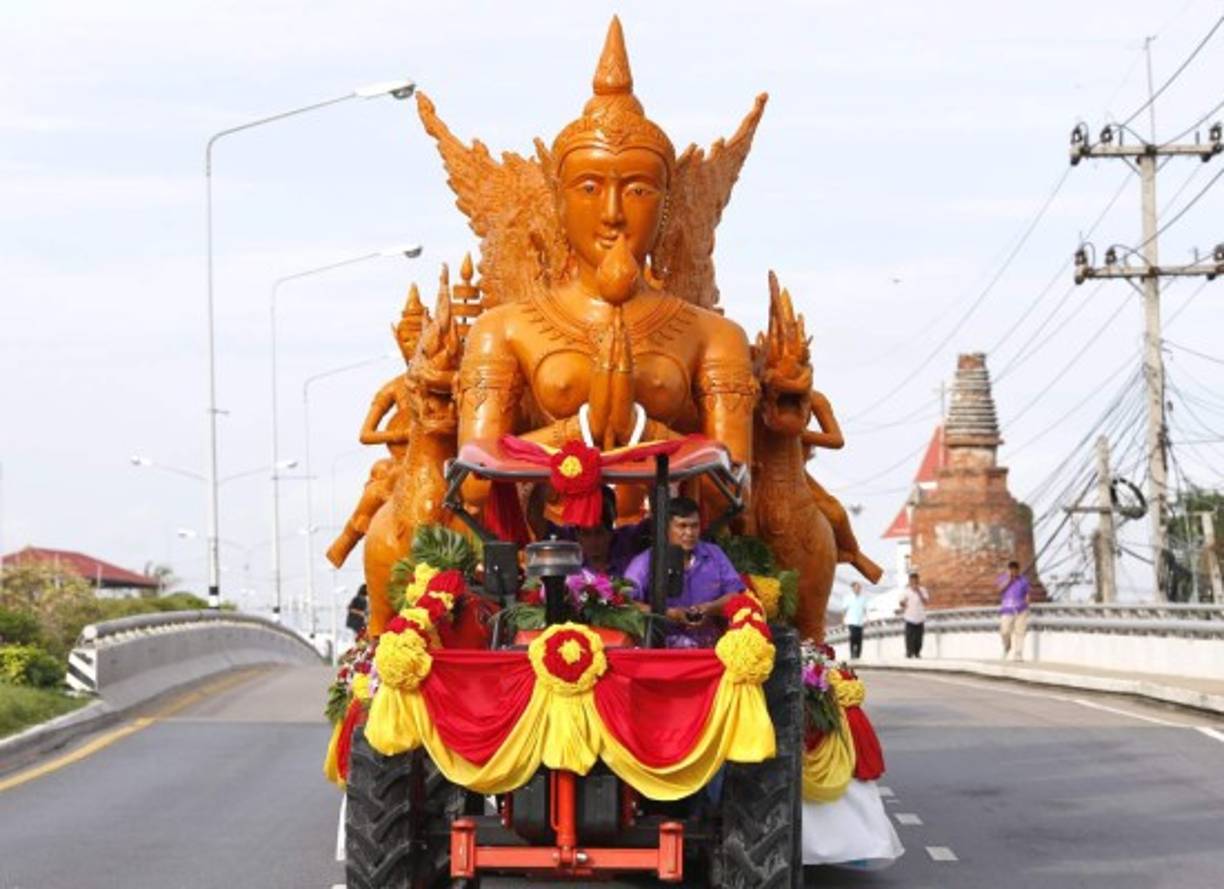 TAILANDIA. Cuaresma budista. Un hombre conduce un tractor que carga varias figuras de la mitología del budismo hechas en cera.