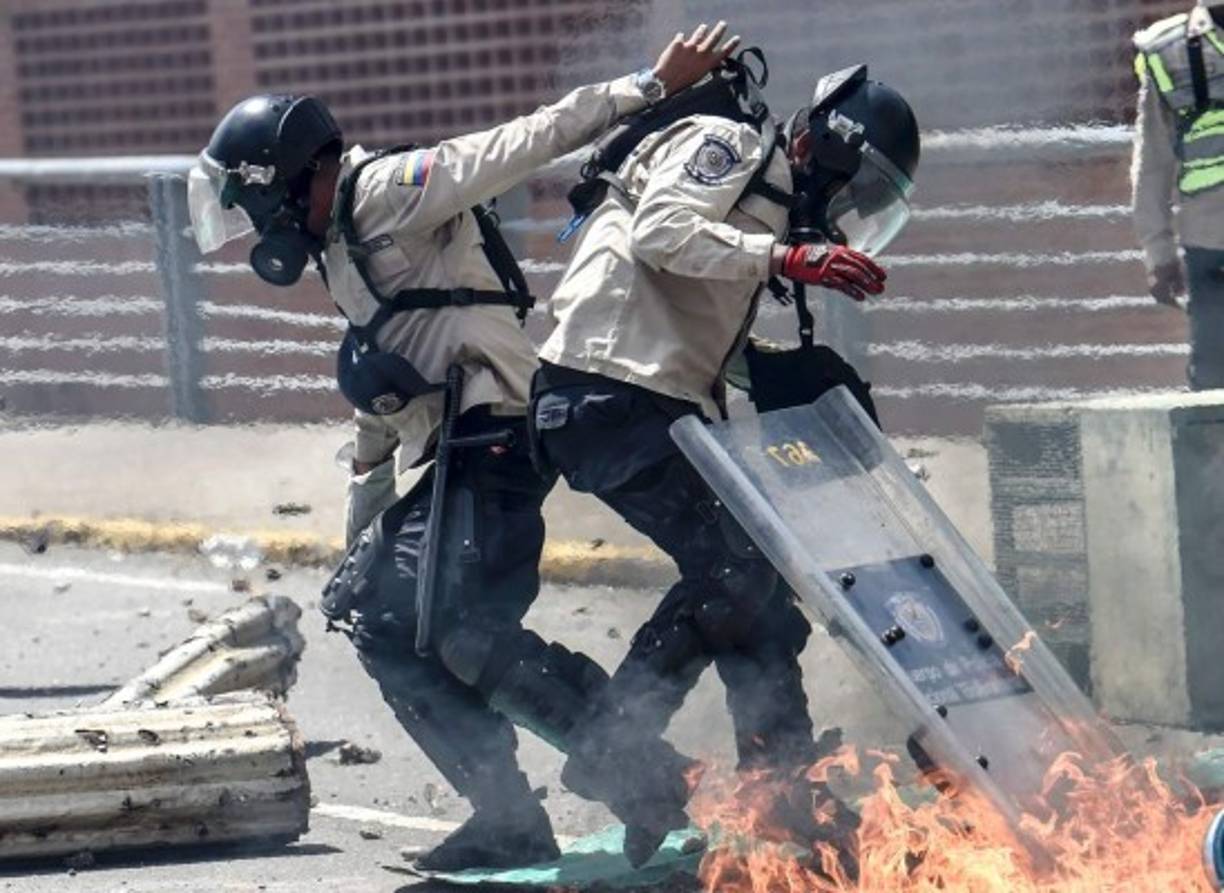 Un policía antimotines ayuda a un compañero, luego de que les arrojaran cocteles molotov.