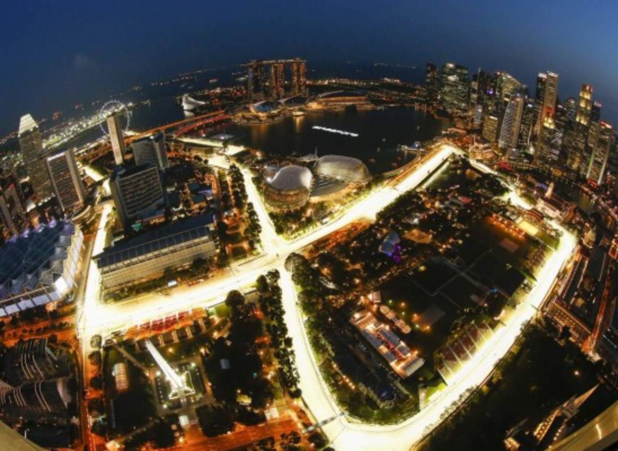FÓRMULA UNO. La hermosa pista los espera. Fotografía aérea que muestra el circuito de Marina Bay en Singapur al anochecer; las luces hacen que el escenario sea un deleite. El Gran Premio de Singapur se celebra este domingo.