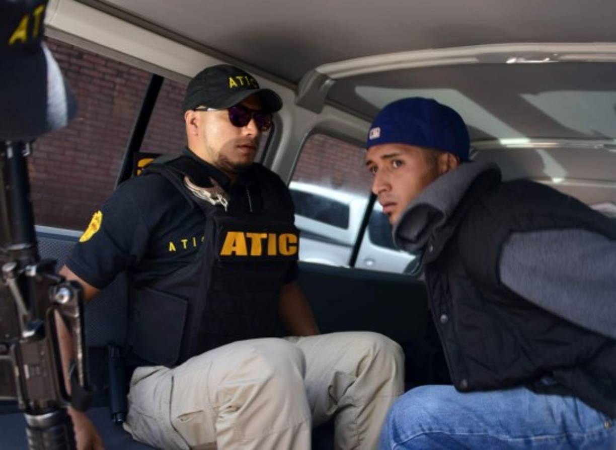 Un joven es llevado detenido en Honduras, custodiado por un agente, durante un operativo en el cual cayeron otros 20 de ellos, informó la Agencia Técnica de Investigación Criminal (ATIC).