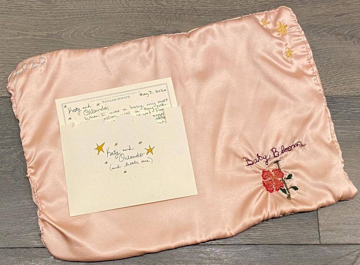 Después del nacimiento de su hija Daisy en 2020, Perry compartió en Instagram fotos del regalo y la dedicatoria que le mandó Taylor a ella y su esposo, Orlando Bloom. Swift le regaló una manta de seda rosa pastel que cosió a mano con bordados personalizados, que incluían estrellas doradas, una flor roja anaranjada, el año en que nació Daisy y “Baby Bloom”, escrito en cursiva.Perry compartió la imagen del regalo con sus seguidores con un mensaje: “espero que (Daisy) lo use durante años hasta que se convierta en un fragmento irreconocible y que lo guarde en su bolsillo cuando sea adolescente”.