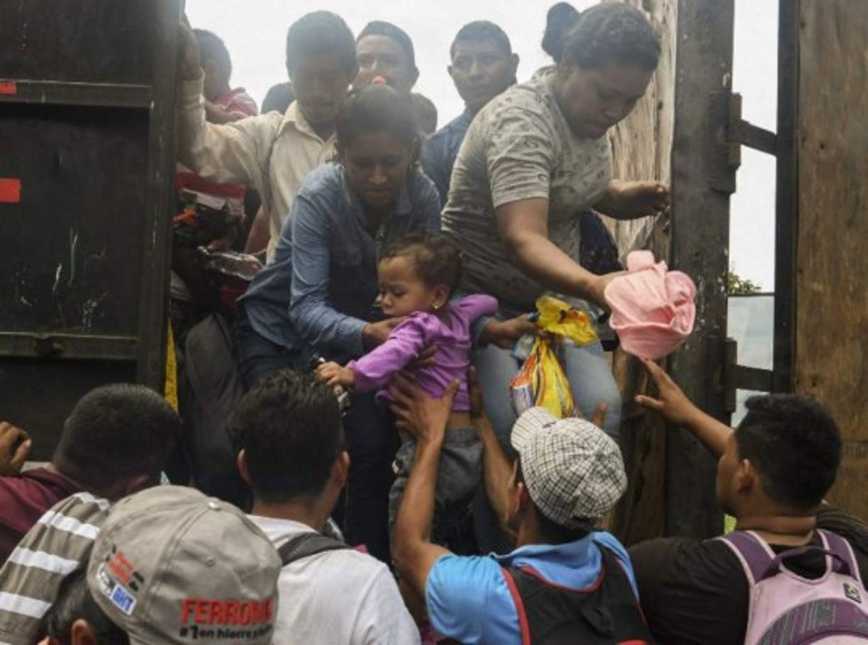 Un grupo de migrantes, niños incluidos, suben a un camión para recorrer parte del camino.