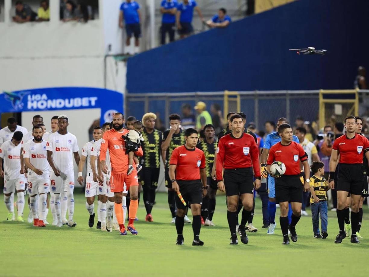 Los jugadores de Real España y Olimpia saliendo a la cancha del estadio Morazán junto con la cuarteta arbitral.