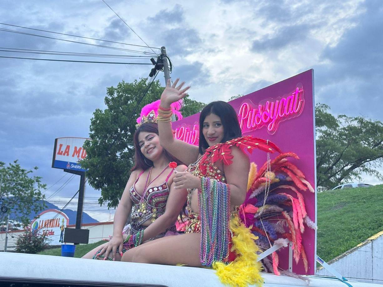 Dos mujeres de la disco night club Pink Pussycat tiran collares a los que asisten al desfile de carroza.