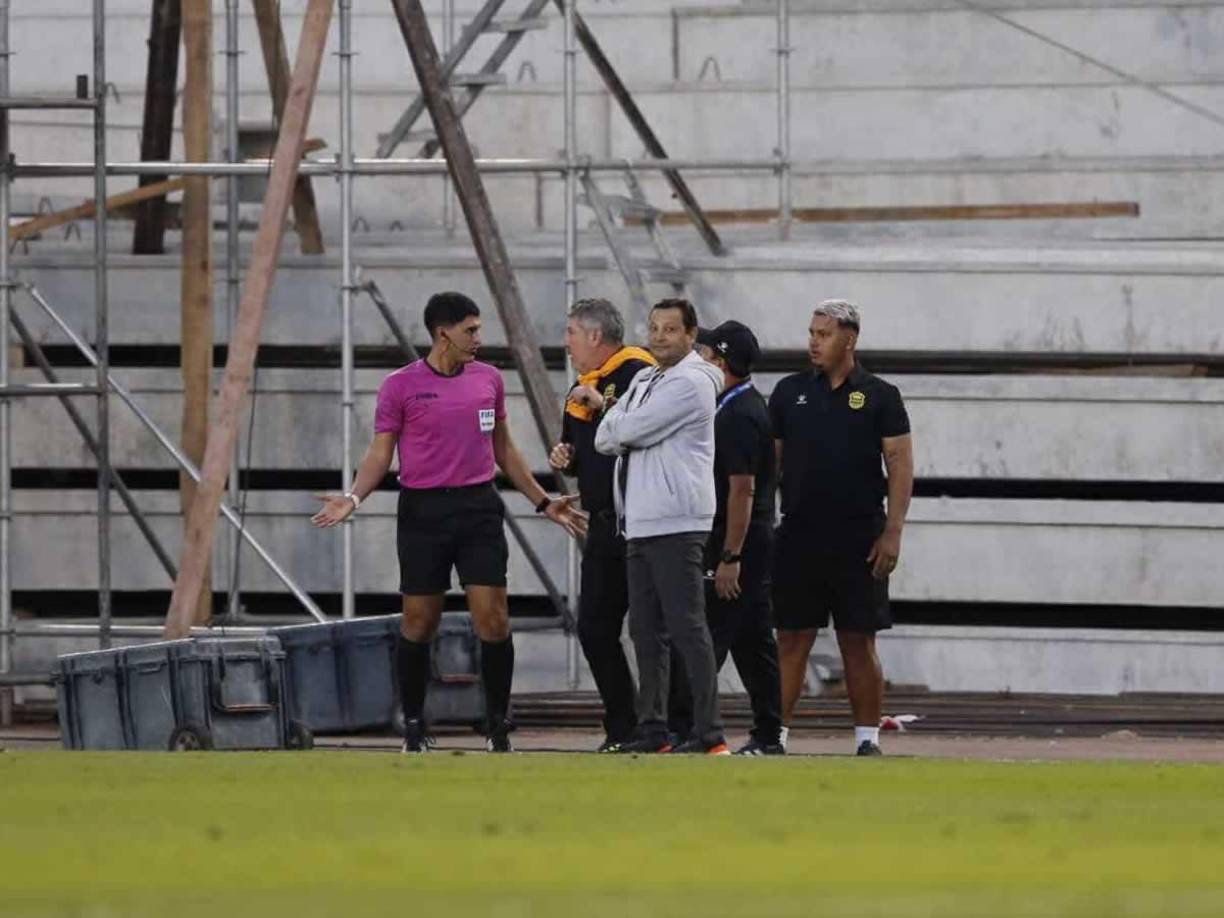 Jeaustin Campo y su cuerpo técnico charlando con el cuarto árbitro del partido.
