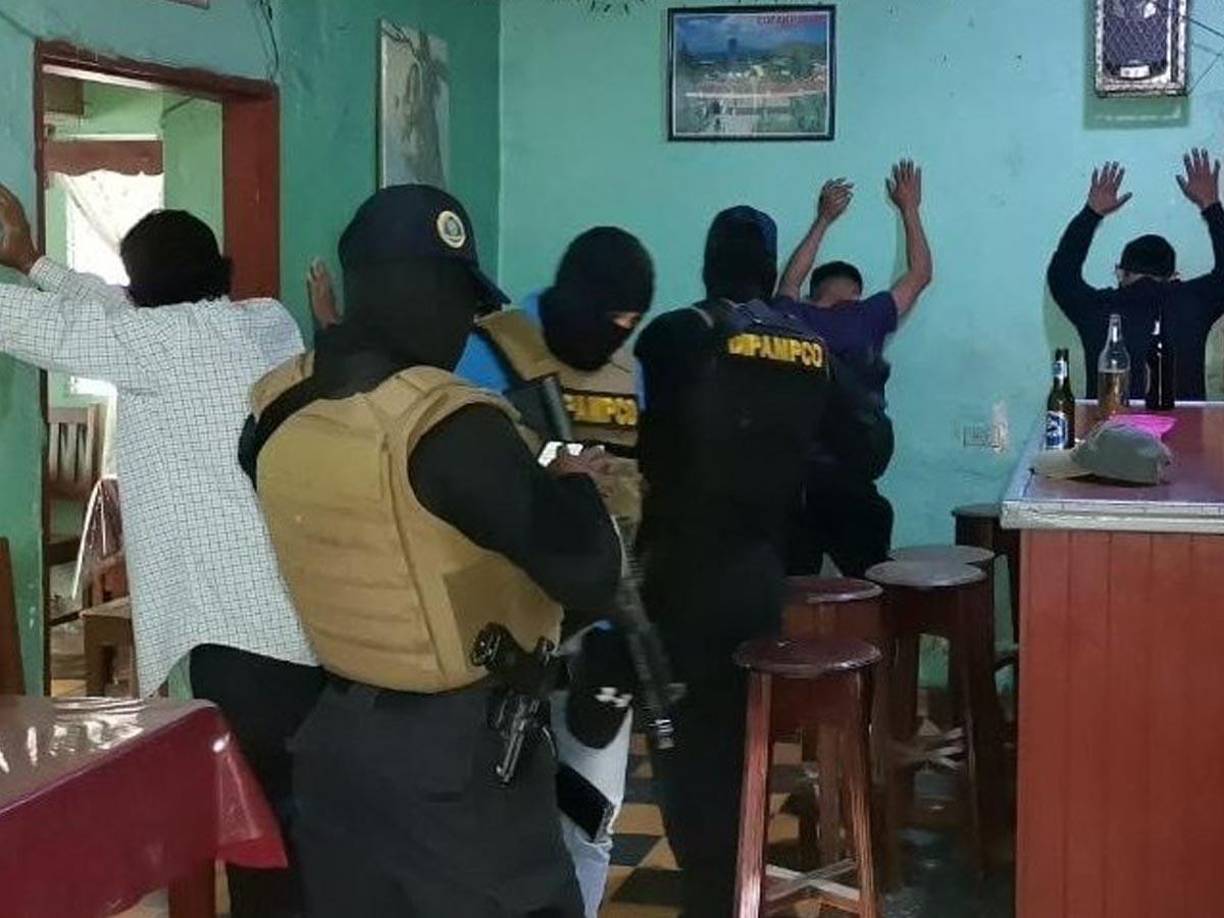 Agentes de la Dirección Policial Anti Maras y Pandillas Contra el Crimen Organizado (DIPAMPCO) revisan a unos hombres en un negocio de bebidas alcohólicas.