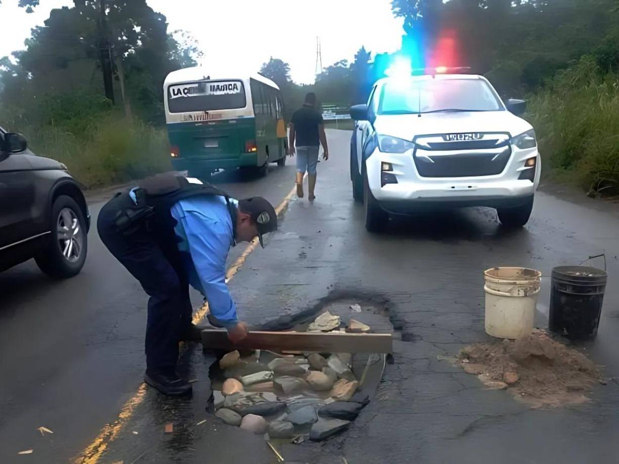 Policías del departamento de Atlántida se han dado a la tarea de apoyar la labor de tapar los enormes baches que hay en la carretera CA-13. 