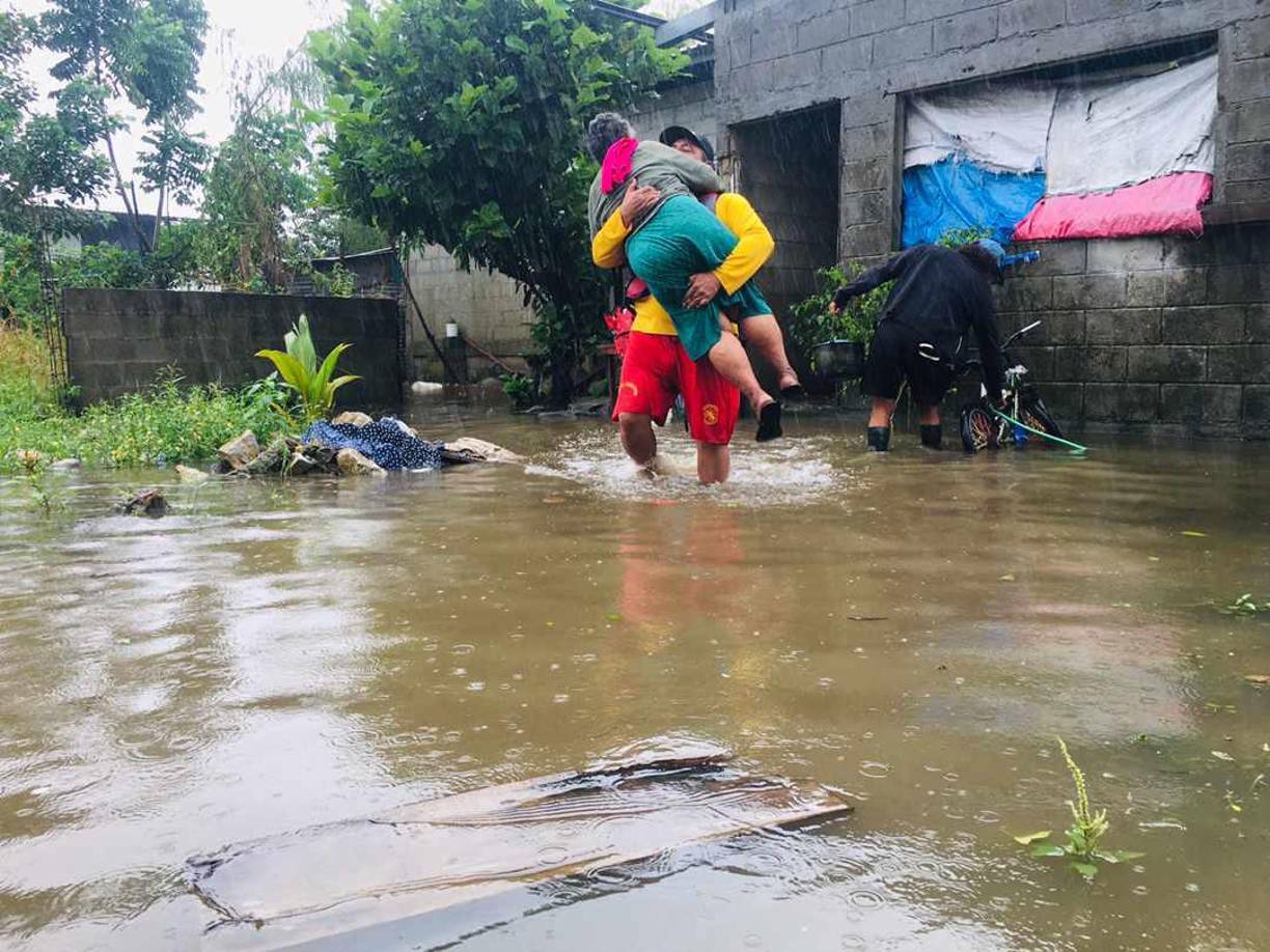 La anciana, cargada en brazos por un agente bomberíl fue trasladada a una volqueta municipal para ser llevada a un albergue temporal del Centro Comunal de San Roque, Puerto Cortés.