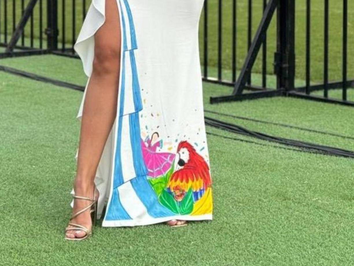 En la parte inferior el vestido tiene plasmado los colores de la bandera de Honduras, pintada una guacamaya y una bailarina de danza folclórica. 